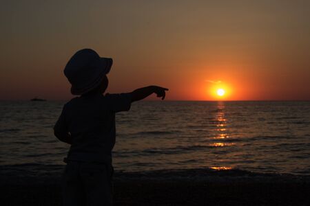 little boy standing back and enjoy the sunsetの写真素材
