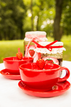 Sweet strawberry jam in a sunny summer day with a tea in the red cupの写真素材