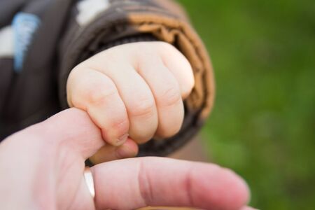 Small childrens hands holding the hand of a parentの写真素材