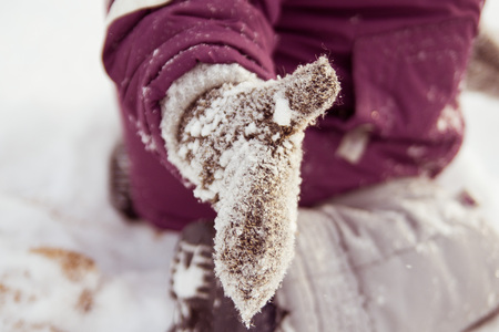 Childrens hand in the mitten in the snowの写真素材