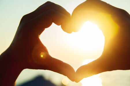 Heart of the hands against the skyの写真素材