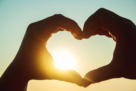 Heart of the hands against the skyの写真素材