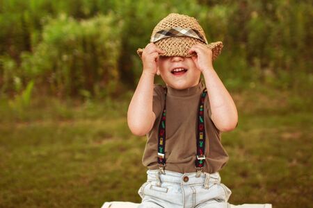 boy hiding his face with his hat and smilingの写真素材