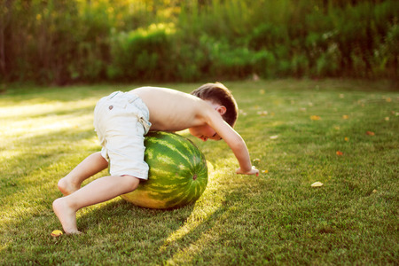 child rolling on the grass watermelonの写真素材