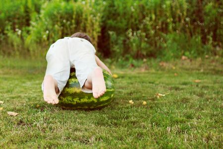 child rolling on the grass watermelonの写真素材