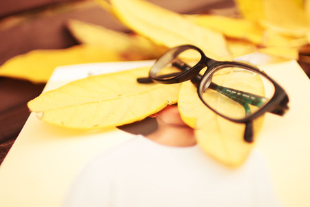 glasses with a magazine on a bench in autumn parkの写真素材