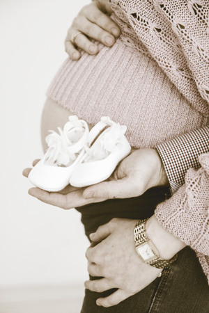 Pregnant woman holding booties from stomachの写真素材
