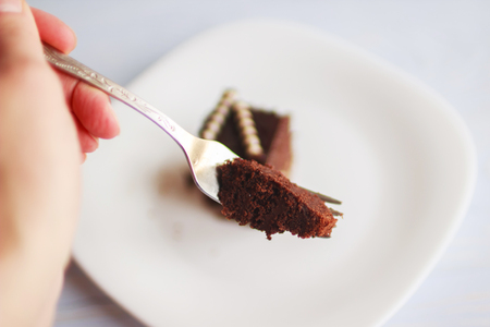 hand holding a fork with a piece of cakeの写真素材