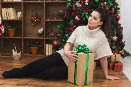 girl sits near a Christmas tree with giftsの写真素材