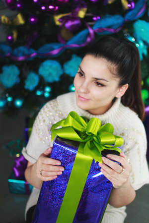 girl sits near a Christmas tree with giftsの写真素材