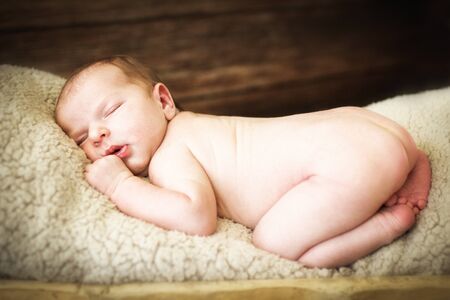 Newborn baby sleeping on a wooden background in the troughの写真素材