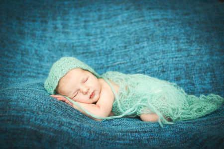 newborn baby sleeping sweetly on a blue rug in blue capの写真素材