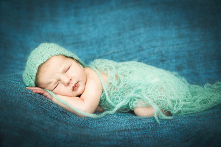 newborn baby sleeping sweetly on a blue rug in blue capの写真素材