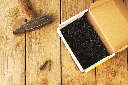 box with screws and tools on a wooden background