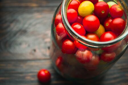 cherry tomatoes in a glass jar on a wooden backgroundの写真素材