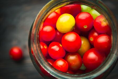 cherry tomatoes in a glass jar on a wooden backgroundの写真素材