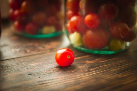 cherry tomatoes in a glass jar on a wooden backgroundの写真素材
