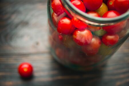 cherry tomatoes in a glass jar on a wooden backgroundの写真素材