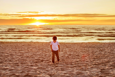 boy goes on sand on the beach. sea ??at sunset