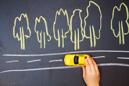 child playing with the car close. one small car goes on the roadの写真素材