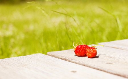 Strawberries on a wooden background. Strawberry against the background of the green grassの写真素材