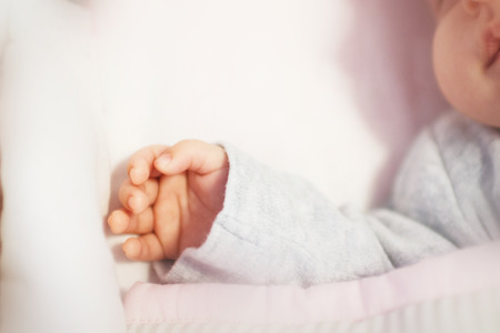 newborn baby lies in the little cradle. hand of a newbornの写真素材