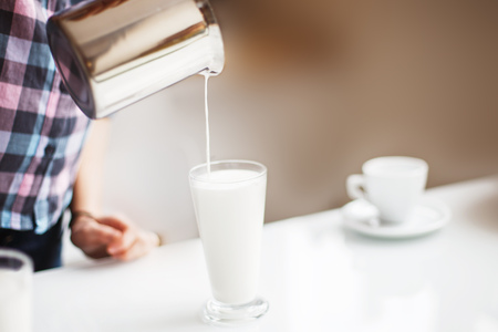 the girl is preparing morning coffee. the girl is preparing breakfast. the girl pours milk in a latteの写真素材
