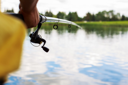 a man with a fishing rod on the river bank is fishingの写真素材