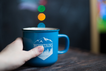 a cup in hand on the wooden background . Christmas bokehの写真素材