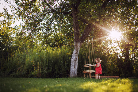 girl in the garden playing with swings.  baby playing in the gardenの写真素材