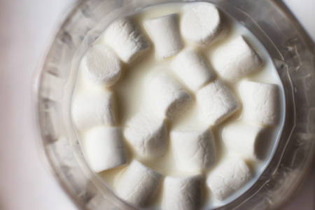marshmallow in a glass of milk. marshmallows on a white background