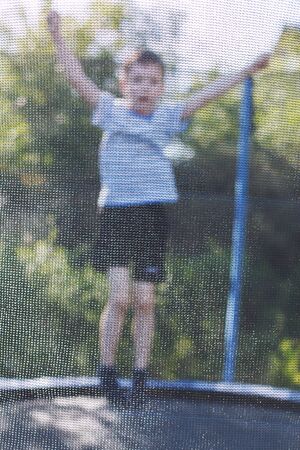 boy jumping on trampoline. the child plays on a trampoline outdoorの写真素材