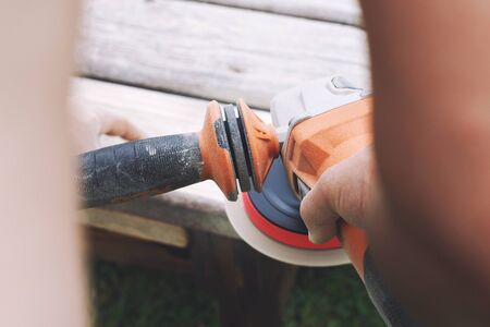 man polishes the board on the bench. man repairing bench in the garden