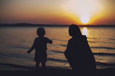 mom and daughter on the beach watching the sunset