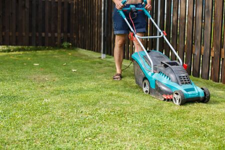 a man mows a lawn with a lawn mower