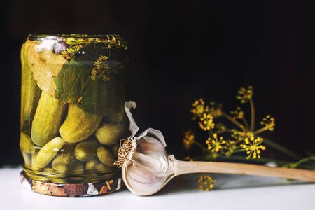 pickled cucumbers in a glass jar with garlic and dill on a dark background.  inverted jar with cucumbers closeの写真素材