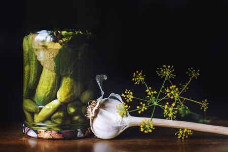pickled cucumbers in a glass jar with garlic and dill on a dark background.  inverted jar with cucumbers closeの写真素材