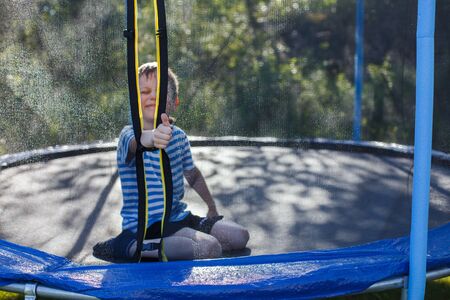 boy jumping on trampoline. child plays  and shows thumb upの写真素材