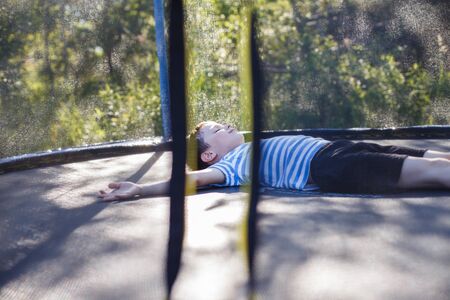 boy on  the trampoline. the child lies on a trampoline and restsの写真素材