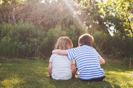 children hugging in the garden at the sunset. brother with  his little sister outdoor backの写真素材