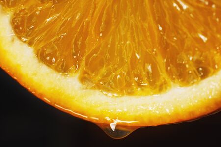 orange slice with a drop of water close up on a black backgroundの写真素材