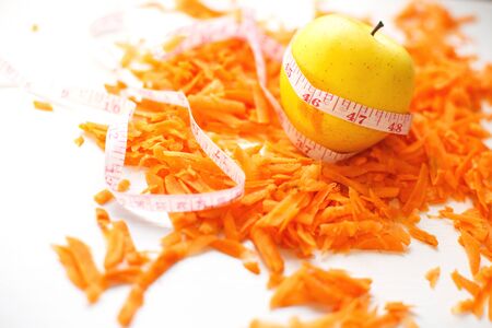 chopped carrots and apple on a white background. fruits and vegetables healthy food for dietの写真素材