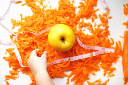chopped carrots and apple. child takes an apple. fruits and vegetables healthy food for dietの写真素材
