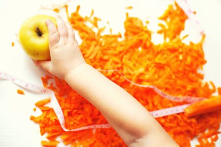 chopped carrots and apple. child takes an apple. fruits and vegetables healthy foodの写真素材