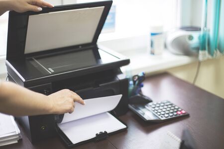 girl in the office prints documents on a printer. girl at work in the office