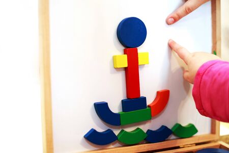 child plays wooden magnetic educational game. girl plays with a toy on a white background.の写真素材