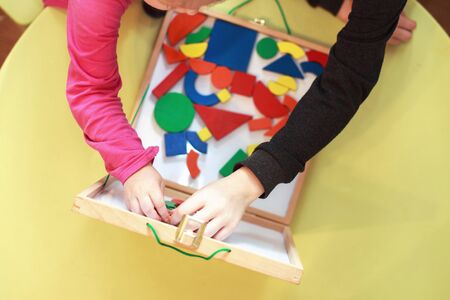 children play wooden magnetic educational games together. view from above. kids play with a...