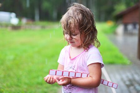 Adorable girl walking with toy at rainy dayの写真素材
