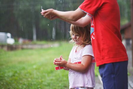 brother and sister play in rainy weather Children jump in puddle and mud in the rain.の写真素材
