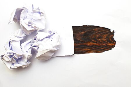Crumpled up papers with a sheet of blank paper on wooden backgroundの写真素材
